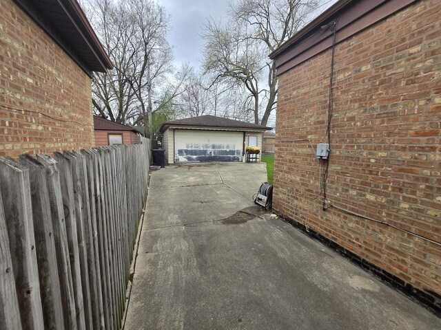 view of home's exterior with an outdoor structure, a garage, fence, and brick siding