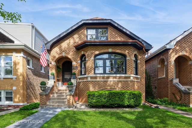 tudor-style house featuring brick siding and a front lawn