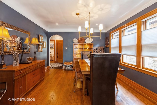 dining area with arched walkways, healthy amount of natural light, wood finished floors, and baseboards