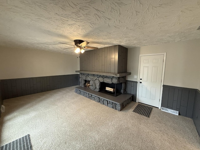 405 9th St, Mazon, IL 60444 - unfurnished living room featuring a wainscoted wall, a fireplace, a ceiling fan, and a textured ceiling
