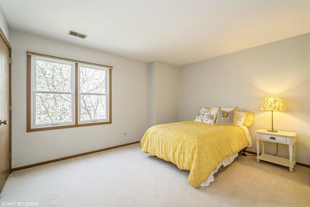 bedroom with baseboards, light carpet, and visible vents