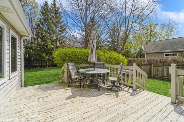 wooden terrace with a lawn, outdoor dining space, and a fenced backyard