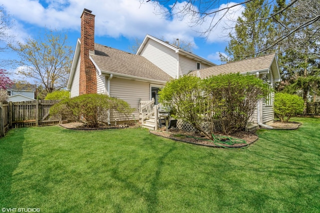 rear view of house featuring roof with shingles, a wooden deck, a fenced backyard, a chimney, and a yard