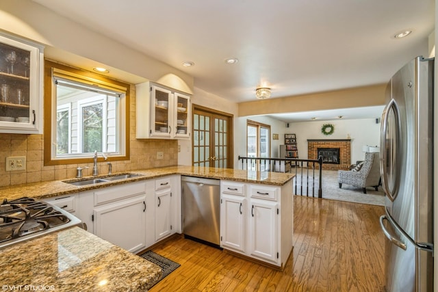 kitchen with a peninsula, appliances with stainless steel finishes, a wealth of natural light, and a sink