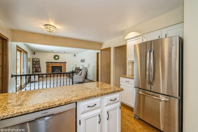 kitchen featuring a fireplace, light wood-style floors, open floor plan, white cabinetry, and stainless steel appliances