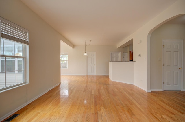 1120 Redwood Ln, Minooka, IL 60447 - spare room featuring light wood-style floors, arched walkways, baseboards, and visible vents