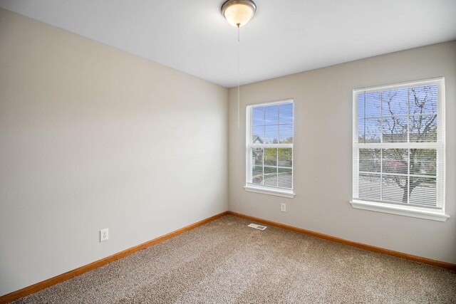 spare room featuring visible vents, carpet, and baseboards