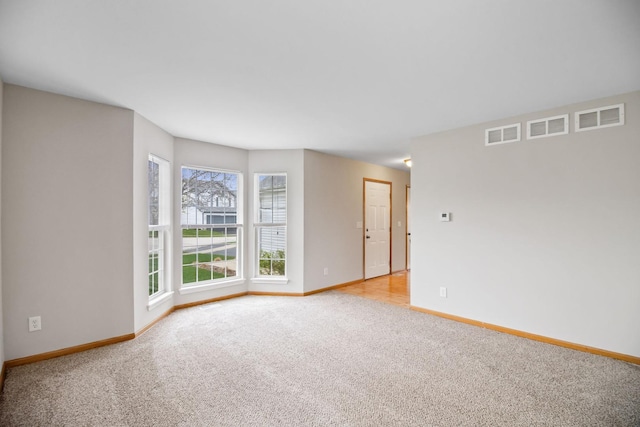 empty room with light colored carpet, baseboards, and visible vents