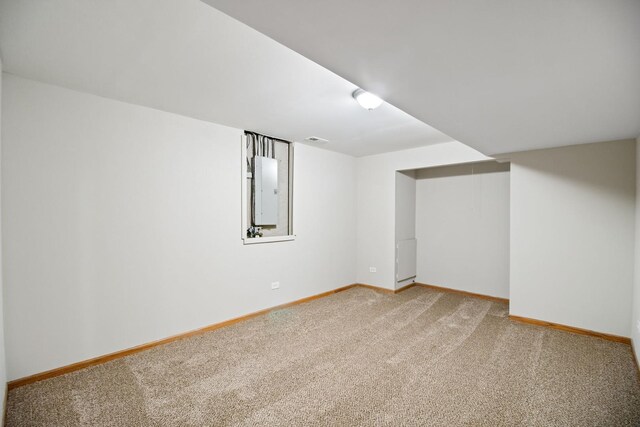 finished basement featuring baseboards, electric panel, and light carpet