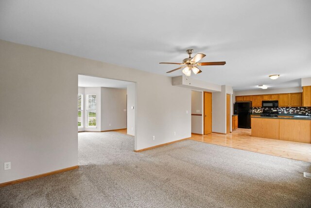 unfurnished living room with baseboards, ceiling fan, and light carpet