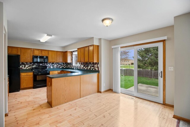 kitchen featuring decorative backsplash, a peninsula, black appliances, and dark countertops