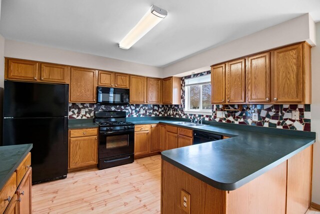 kitchen featuring dark countertops, brown cabinetry, a sink, and black appliances
