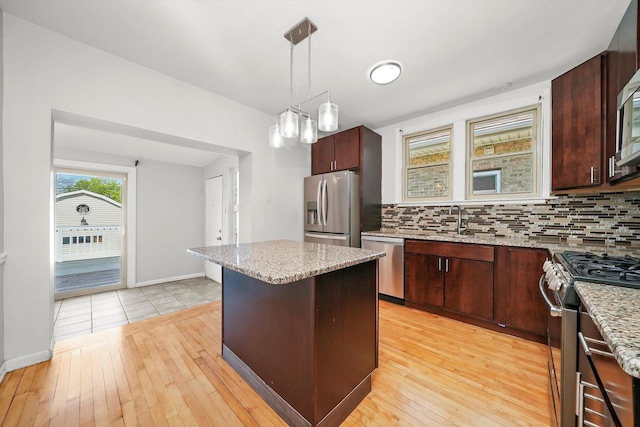 2910 N 76th Ct, Elmwood Park, IL 60707 - kitchen featuring appliances with stainless steel finishes, decorative backsplash, a kitchen island, and hanging light fixtures