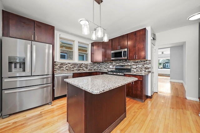 2910 N 76th Ct, Elmwood Park, IL 60707 - kitchen featuring stainless steel appliances, backsplash, light wood-type flooring, a center island, and hanging light fixtures