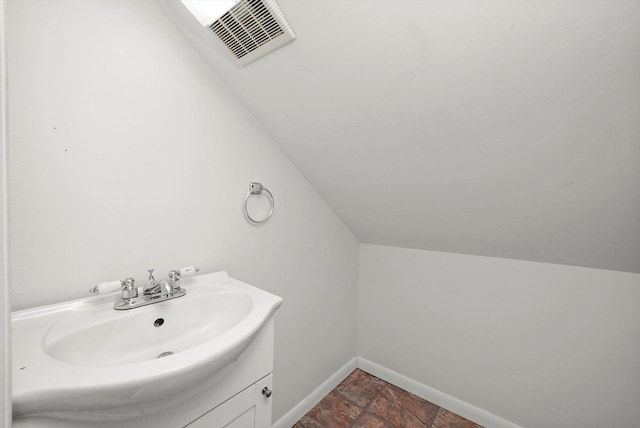 2910 N 76th Ct, Elmwood Park, IL 60707 - bathroom featuring baseboards, lofted ceiling, stone finish floors, and vanity