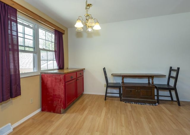 dining room featuring light wood-style floors, baseboards, and an inviting chandelier