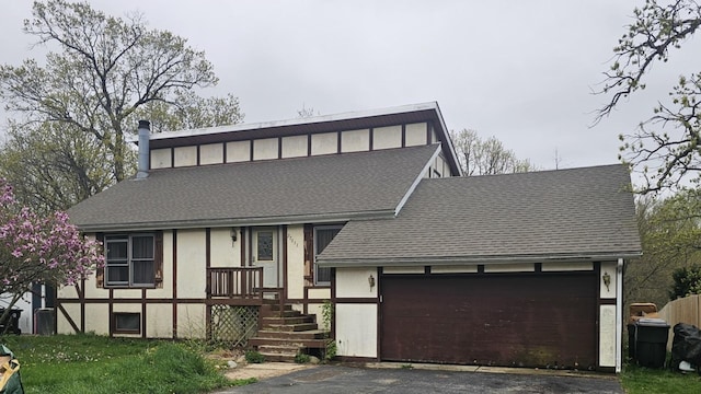 view of front of property featuring an attached garage, a shingled roof, and driveway