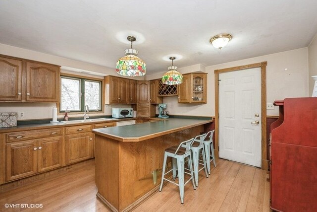 27833 W Bayview Dr, Ingleside, IL 60041 - kitchen with brown cabinets, light wood-type flooring, a sink, and a kitchen bar