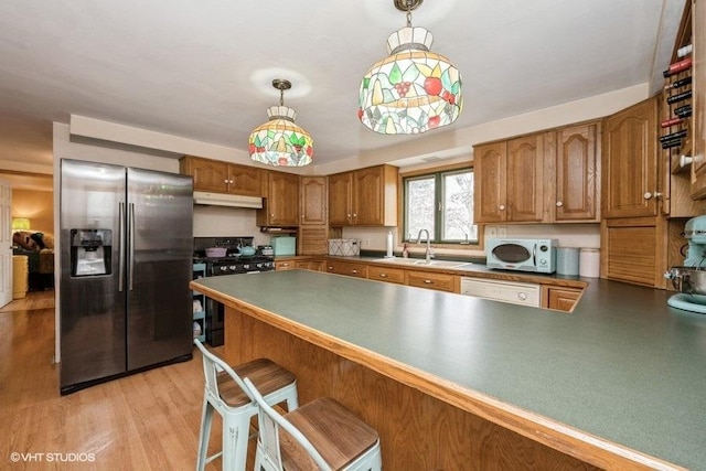 27833 W Bayview Dr, Ingleside, IL 60041 - kitchen with stainless steel fridge, brown cabinets, a sink, black range with gas cooktop, and under cabinet range hood