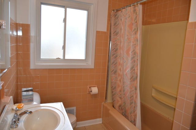 bathroom featuring tile walls, plenty of natural light, and a sink