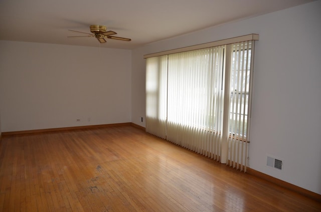 empty room featuring light wood-style floors, baseboards, a ceiling fan, and visible vents