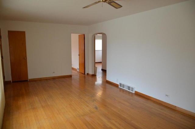 unfurnished room featuring visible vents, baseboards, ceiling fan, arched walkways, and light wood finished floors
