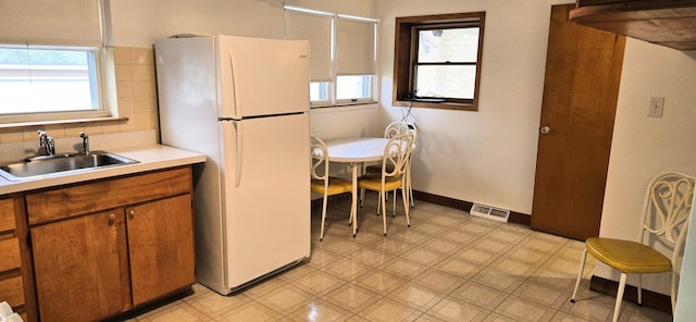 kitchen featuring visible vents, freestanding refrigerator, light floors, light countertops, and a sink