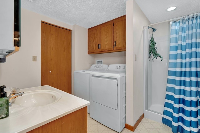 laundry area with laundry area, washing machine and dryer, light floors, a textured ceiling, and a sink