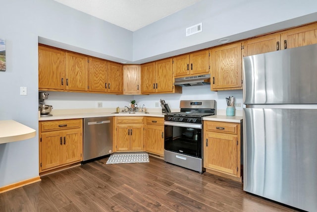 kitchen with visible vents, dark wood-type flooring, under cabinet range hood, a sink, and stainless steel appliances