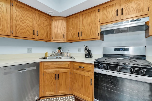 kitchen featuring brown cabinetry, light countertops, under cabinet range hood, a sink, and stainless steel appliances