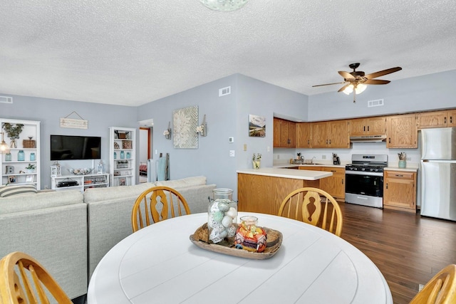 dining space with a ceiling fan, a textured ceiling, visible vents, and dark wood-type flooring