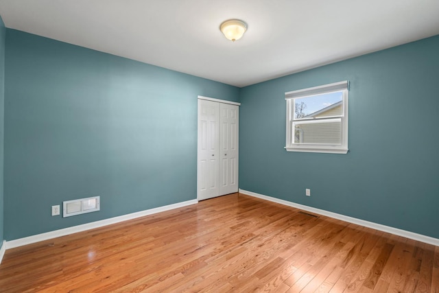 empty room with baseboards, visible vents, and wood finished floors