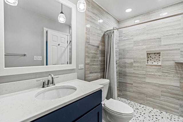 full bathroom featuring toilet, tiled shower, and vanity