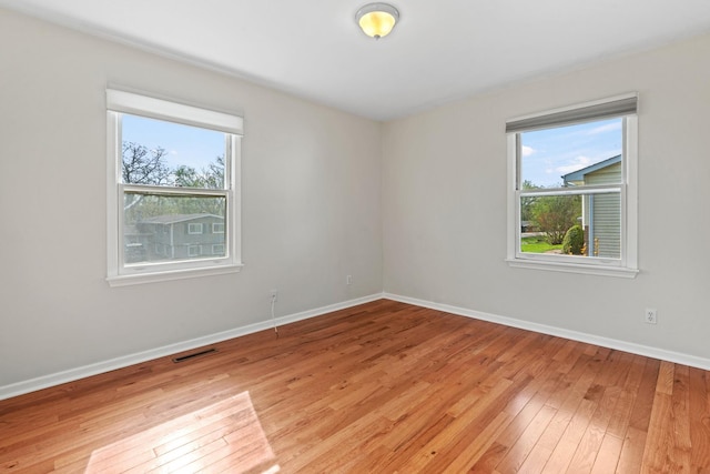 spare room with baseboards, light wood-style flooring, and visible vents