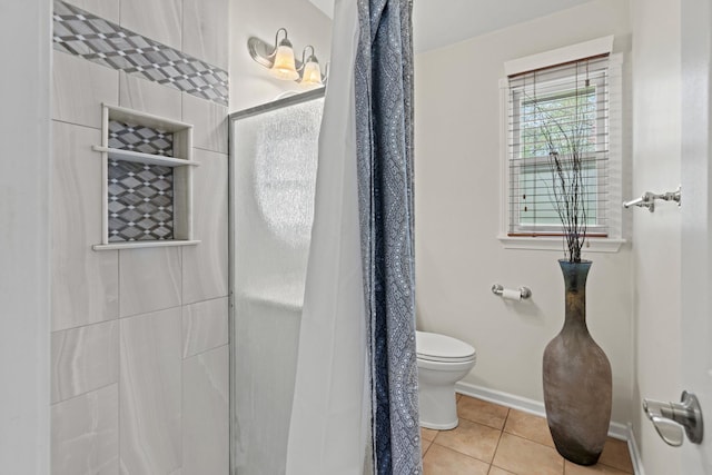 bathroom with baseboards, tile patterned flooring, a shower stall, and toilet