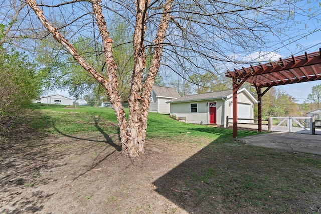 view of yard featuring a gate, a garage, fence, an outdoor structure, and a pergola