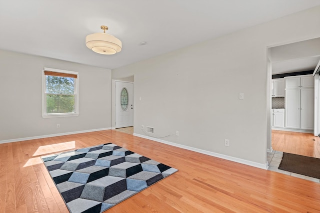 spare room featuring baseboards, light wood finished floors, and visible vents