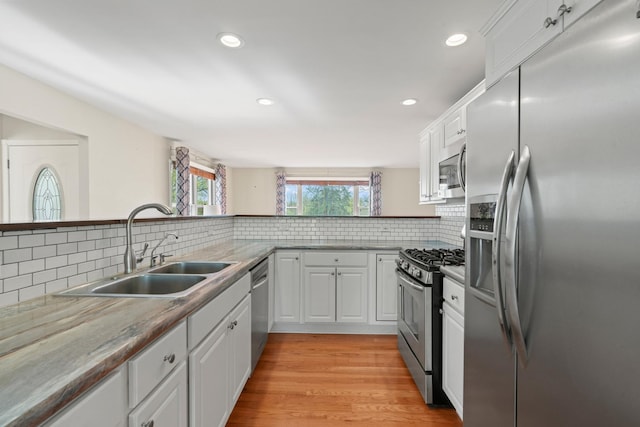 kitchen featuring white cabinets, appliances with stainless steel finishes, a sink, recessed lighting, and backsplash