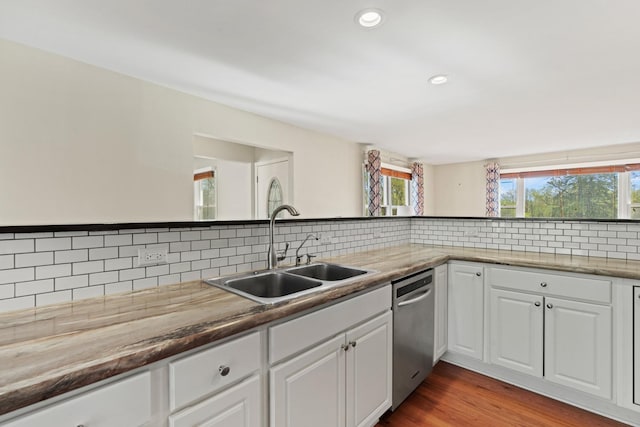 kitchen featuring stainless steel dishwasher, a sink, backsplash, and a wealth of natural light