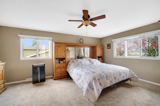 bedroom featuring baseboards, multiple windows, and light carpet