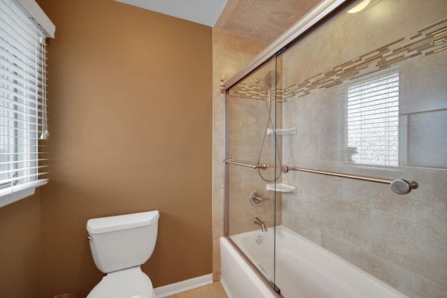 full bathroom with toilet, baseboards, and bath / shower combo with glass door