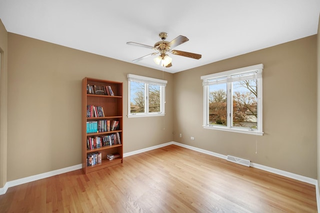 empty room with visible vents, baseboards, wood finished floors, and a wealth of natural light
