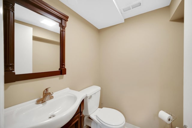 half bath with visible vents, baseboards, toilet, and vanity