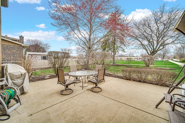view of patio featuring fence, outdoor dining space, and a grill