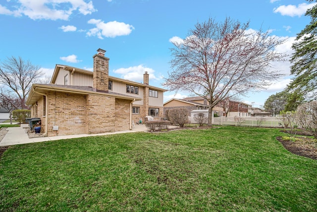 back of property featuring fence, a chimney, a yard, and a patio area