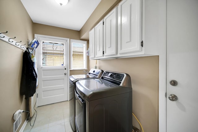 clothes washing area featuring separate washer and dryer, cabinet space, and light tile patterned floors