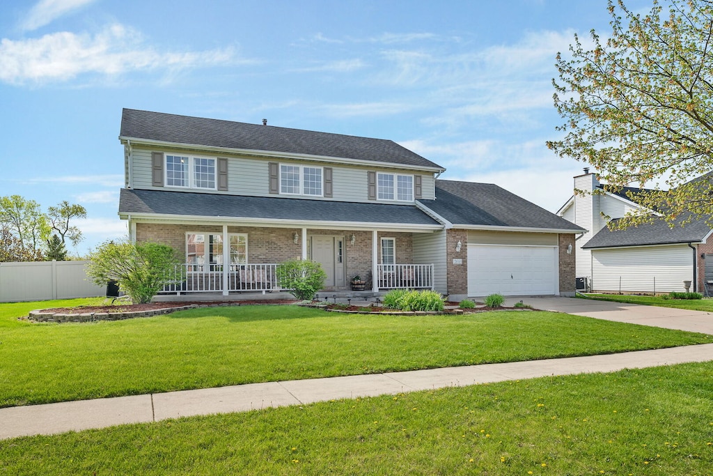26165 W Leslie Dr, Channahon, IL 60410 - view of front of house featuring a porch, driveway, brick siding, fence, and an attached garage