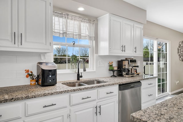 kitchen featuring a sink, dishwasher, white cabinets, and light stone countertops