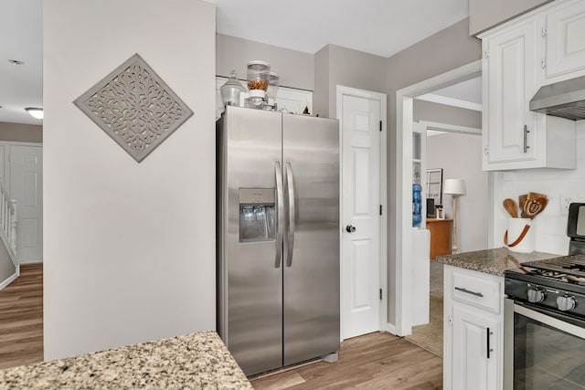kitchen featuring white cabinets, stainless steel appliances, light wood-type flooring, and under cabinet range hood