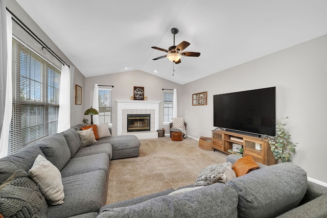 living room with baseboards, a tile fireplace, a ceiling fan, carpet, and vaulted ceiling